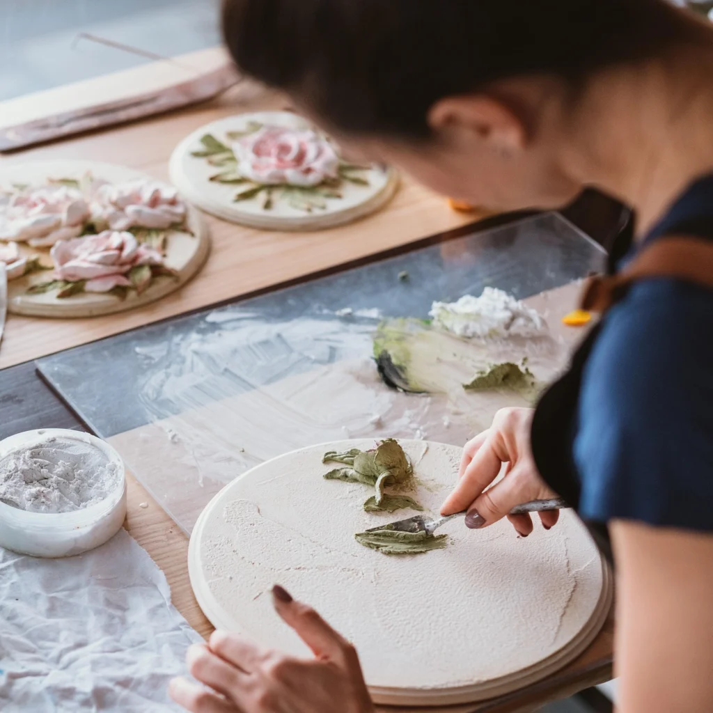 Artisan hand-sculpting rose details on a clay and resin decorative plate