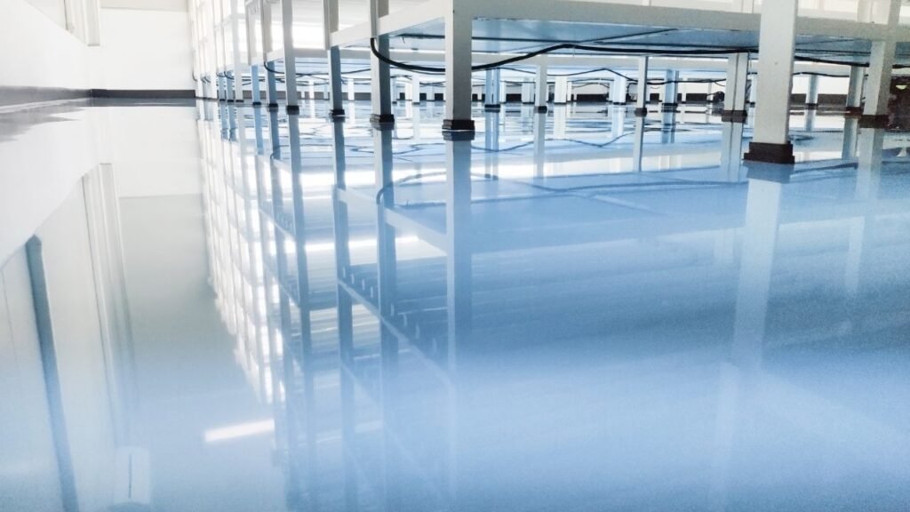 Finished glossy blue epoxy floor reflecting warehouse shelving and lights