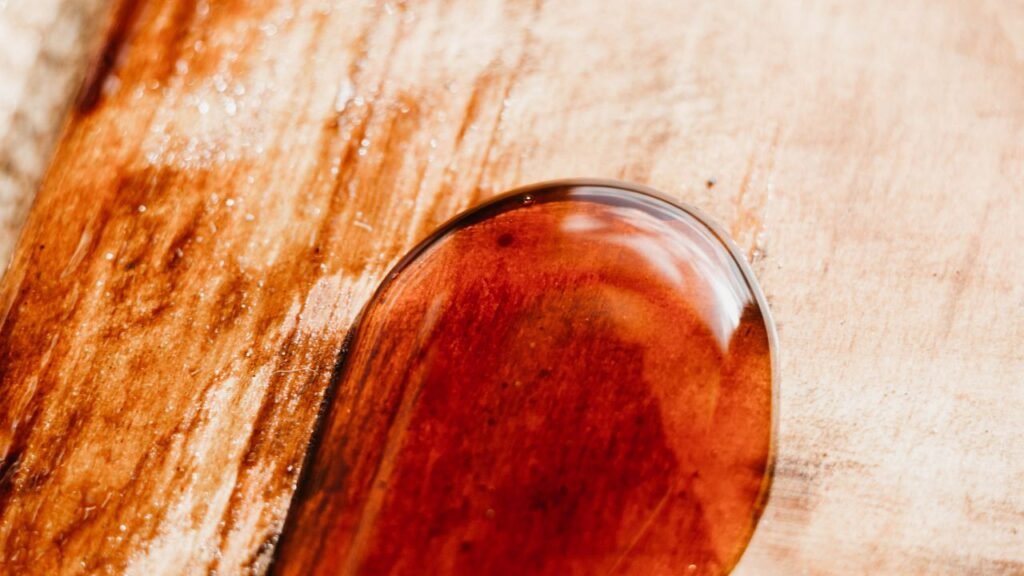 Macro shot of crystal-clear cured epoxy resin droplet showing high clarity on wood surface