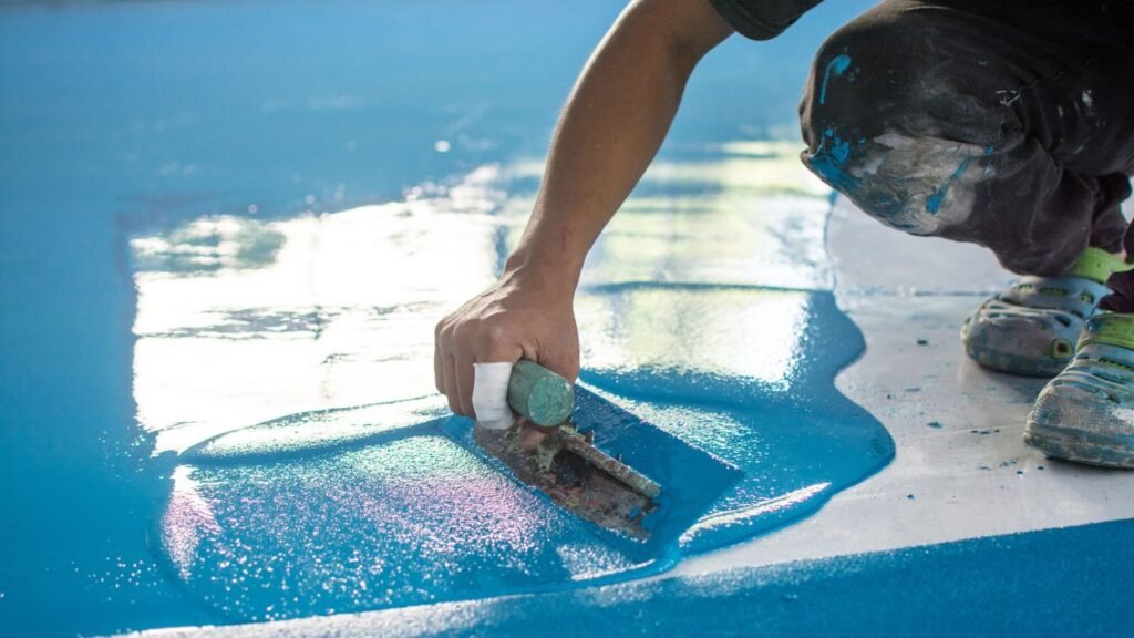 Applying shimmering holographic blue epoxy floor coating with a metal trowel