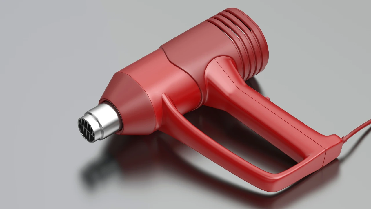 Red heat gun on a gray background, a tool used to soften cured resin for easier removal from metal