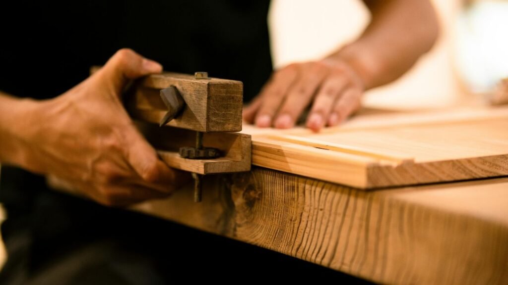 Wooden hand clamp securing a plank in preparation for epoxy application